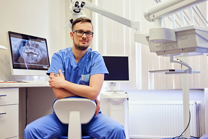 Male dentist in a room with medical equipment on background.